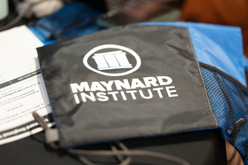 A photo of a Maynard Institute branded tote bag and a conference agenda.