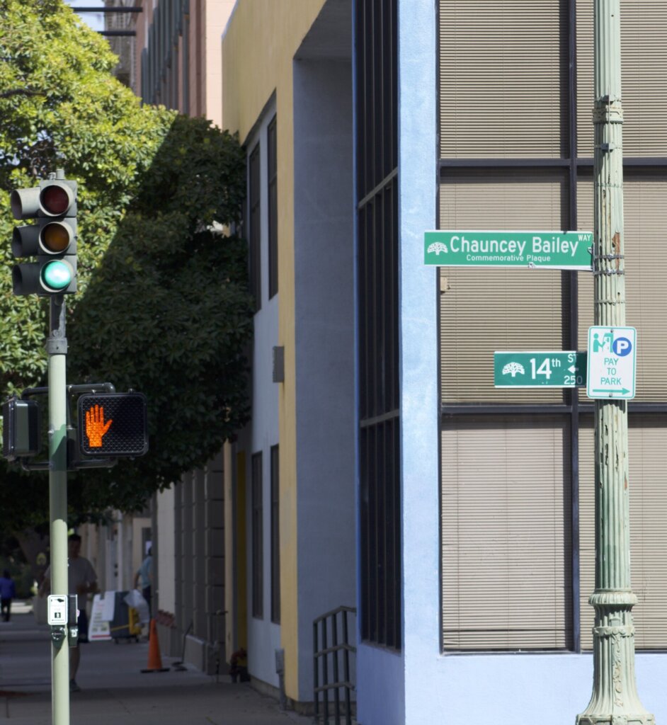 A photo of the intersection and street sign at Chauncey Bailey way and 14th street in Oakland.
