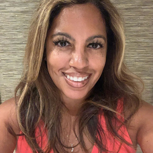 A photo of Sarah Allen, a Black woman with long eyelashes, a pink shirt, and medium hair in various shades and highlights.